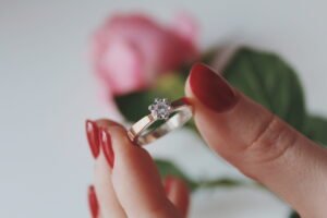 closeup shot female holding gold diamond ring with pink rose 1 scaled 1
